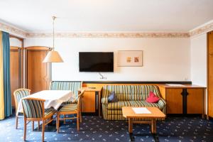 ein Hotelzimmer mit einem Sofa und einem Tisch in der Unterkunft Hotel Reipertingerhof in Bruneck