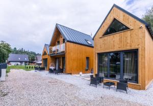 une maison en bois avec un toit noir et des chaises noires dans l'établissement Aparthome Tatra, à Biały Dunajec