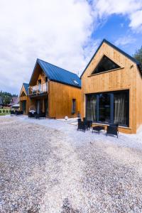 a wooden house on a gravel road with benches at Aparthome Tatra in Biały Dunajec