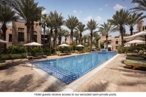 a pool at a resort with palm trees and umbrellas at Jumeirah Dar Al Masyaf in Dubai
