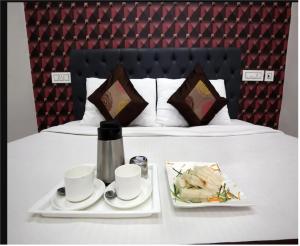 una mesa con dos tazas y platos de comida en una cama en Hotel Cross Road By WB Inn en Unnāo