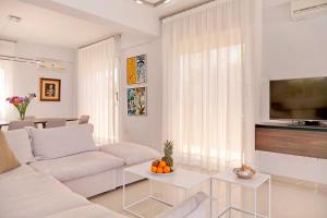 a living room with a white couch and a tv at Velomar Villa in Paralimni