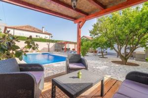 un patio avec des chaises et une table ainsi qu'une piscine dans l'établissement Apartments Villa Odesa with shared pool, à Zadar