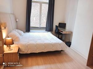 a bedroom with a bed and a desk and a window at Superbe appartement au coeur du quartier européen in Brussels