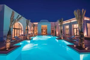 a swimming pool with palm trees in a house at night at La Badira - Adult Only in Hammamet