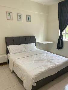 a bedroom with a large bed with white sheets and a window at Trails of Kampar in Kampar