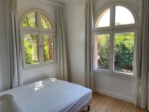 biała sypialnia z 2 oknami i łóżkiem w obiekcie Le colombier, villa vue mer accès plage 300M w mieście Varengeville-sur-Mer