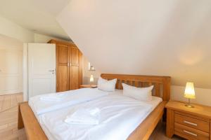 sypialnia z dużym łóżkiem z białą pościelą i poduszkami w obiekcie Ferienhaus Karnin A w mieście Karnin