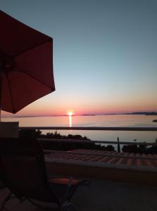 um pôr-do-sol sobre o oceano com uma cadeira e um guarda-chuva em Sunny P em Primošten