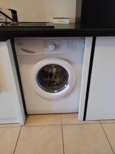 a white washing machine in a kitchen under a counter at APARTAMENTY TR 11 Apartament nr 6 in Olsztyn