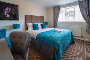 a bedroom with a bed with a blue blanket and a chair at White Lion Hotel in Crewe