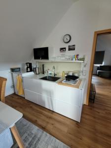 a white kitchen with a sink and a clock on the wall at Apartment Sehring in Oelde