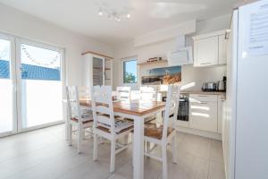 a white kitchen with a wooden table and chairs at Ferienhaus Ulrichshorst in Ulrichshorst