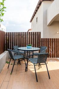 d'une terrasse avec une table, des chaises et une clôture. dans l'établissement Cosy & Calm Central Getaway Modern Guest Suite by Midrachov 1 Queen Bed, à Zikhron Yaakov