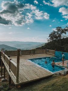 a group of people in a swimming pool on a wooden deck at Chalés do alegre in Capitólio