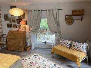 a bedroom with a window and a couch and a chair at Le Coteau du Seigneur in Laize-la-Ville