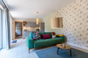 sala de estar con sofá verde y cocina en Haus Silvana, en Zempin