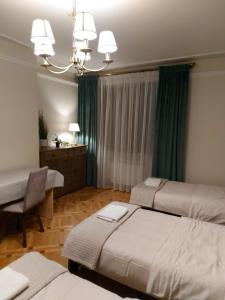 1 dormitorio con 3 camas, escritorio y lámpara de araña en Hostel LUNA en Mińsk Mazowiecki