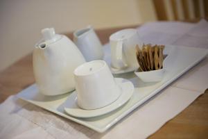 bandeja con tazas blancas y utensilios sobre una mesa en Castelletto Suites, en Cagliari