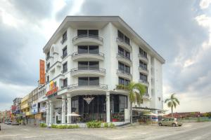 un edificio blanco con un coche aparcado delante de él en Arenaa Batik Boutique, en Kuantan