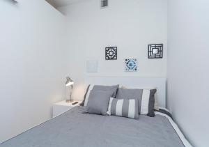 a white bedroom with a bed with gray sheets and pillows at Fantastic 3BR At Financial District in New York