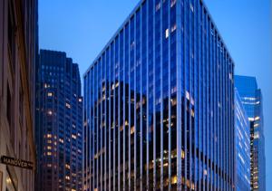 a tall glass building in a city at night at Fantastic 3BR At Financial District in New York