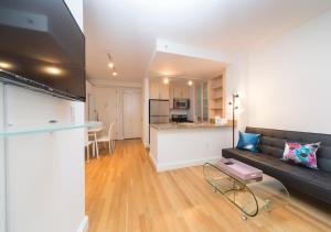 a living room with a couch and a kitchen at Fantastic 3BR At Financial District in New York