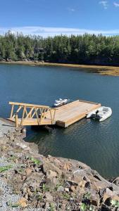 a wooden dock with a boat on the water at The Millhouse Oceanfront Cottage in Summerford