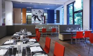 a dining room with tables and red chairs at Lindner Hotel Frankfurt Sportpark, part of JdV by Hyatt in Frankfurt/Main