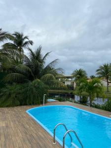 una piscina azul con palmeras en el fondo en Casa de Praia - Interlagos, en Camaçari