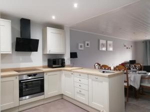 a kitchen with white cabinets and a table with chairs at Lovely Lakeside lodge for families and friends in South Cerney
