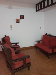 un soggiorno con 2 sedie e un divano rosso di DEPARTAMENTO Alicia 1 a Santiago del Estero