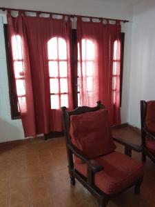 een woonkamer met rode gordijnen en een stoel bij DEPARTAMENTO Alicia 1 in Santiago del Estero