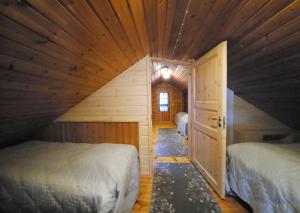 Dormitorio pequeño en el ático con 2 camas y puerta abierta en Kuhahuvila, Kalajärvi, Maatilamatkailu Ilomäen mökit en Peräseinäjoki