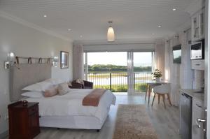 a bedroom with a large bed and a balcony at Serenity Ocean Lodge in Wilderness