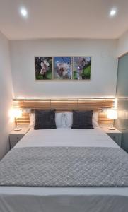 a bedroom with a white bed with three paintings on the wall at Apartamento Happy Place Madrid in Madrid