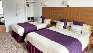 a hotel room with two beds with purple sheets at Magnuson Hotel Sandy Lodge Newquay in Newquay