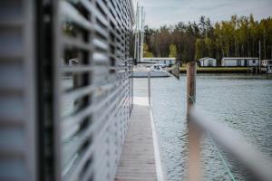 un muelle sobre un cuerpo de agua con un barco en Schwimmendes Haus - Hausboot Trinity en Peenemünde