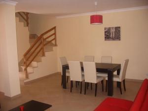 une salle à manger avec une table noire et des chaises blanches dans l'établissement Sol e Mar, à Vila Nova De Cacela