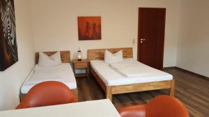 a room with two beds and a chair and a door at Phoenix in Chemnitz