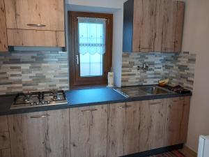 a kitchen with wooden cabinets and a sink and a window at Ca' di Burghi 2 in Busca