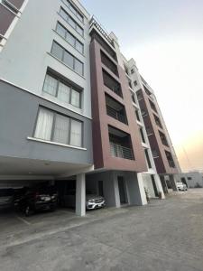 a large building with cars parked in a parking lot at Lovely 3-Bed with a Pool next to Four Point in Lagos