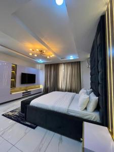 a bedroom with a large bed and a television at Lovely 3-Bed with a Pool next to Four Point in Lagos