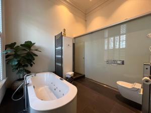 a bathroom with a large tub and a toilet at Suitehotel Pincoffs in Rotterdam