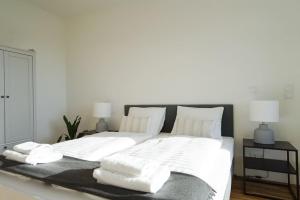 uma grande cama branca com lençóis e almofadas brancos em Apartment with terrace near Metro Station and Spa em Viena