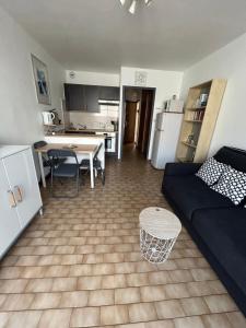 een woonkamer en een keuken met een bank en een tafel bij T2 à côté de la mer quartier des Quilles in Sète