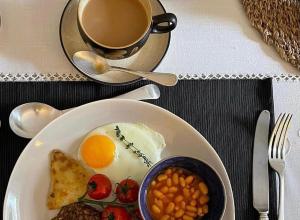 a breakfast plate with eggs beans and a cup of coffee at Heathpark House in Blairgowrie
