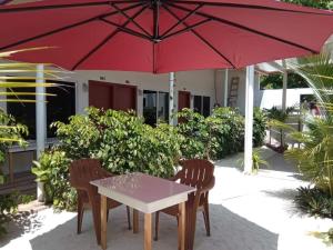 Thoddoo Garden inn في ثودو: طاولة وكراسي تحت مظلة حمراء