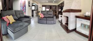 a living room with two couches and a fireplace at Casa nos Ingleses com piscina e jacuzzi in Florianópolis