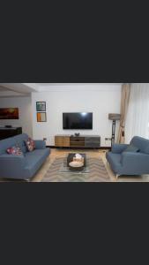 uma sala de estar com dois sofás azuis e uma televisão em Dzorwulu em Trofwi